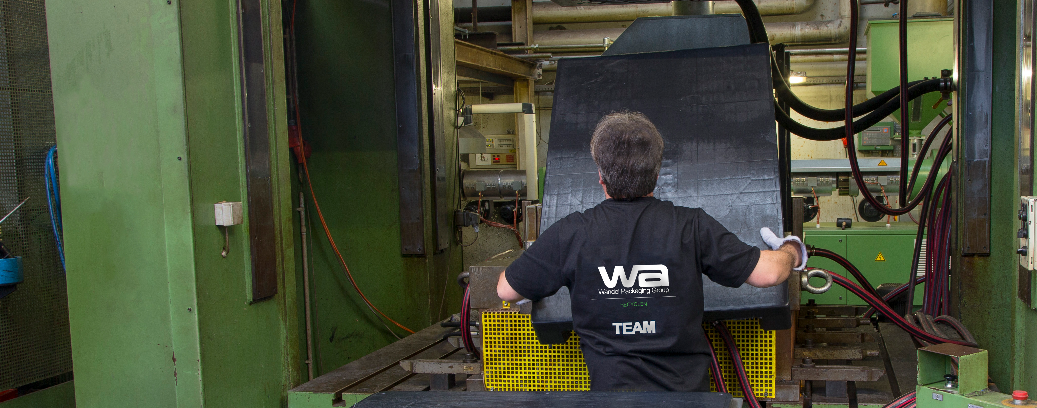 Mitarbeiter hebt Palette aus Tiefziehpresse